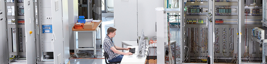 Techniker bei der Inbetriebnahme zwischen Schaltschränken
